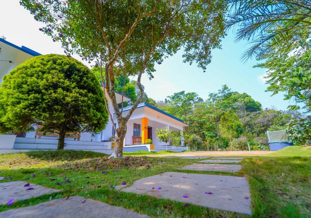 a house with a tree in front of it at Vythiri Silver Mist Hilltop Villa By VOYE HOMES in Vythiri