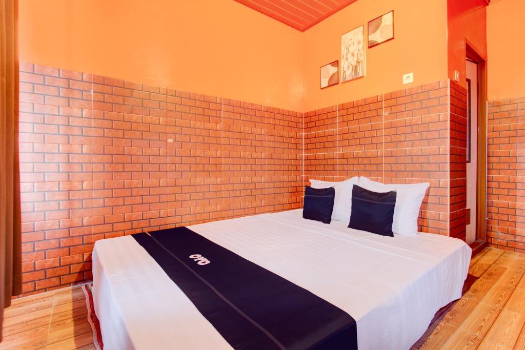 uma cama num quarto com uma parede de tijolos em Collection O 93742 Sidodadi Hotel Dan Resto em Yogyakarta