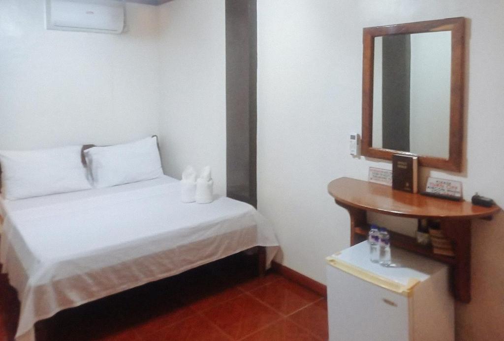 Habitación pequeña con cama y espejo. en RedDoorz at Amphibi-ko Resort Palawan en Corón