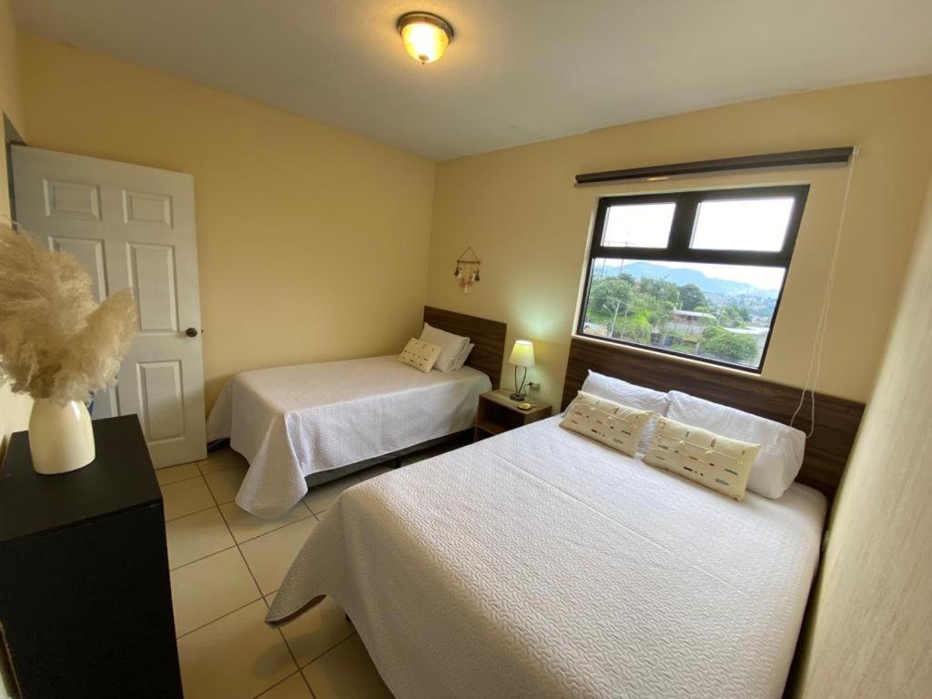 a hotel room with two beds and a window at Mi casa es tu casa. in Quetzaltenango