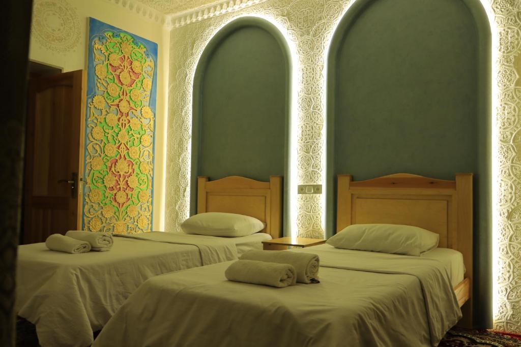 two beds in a room with two archways at Hotel ALISHER in Bukhara