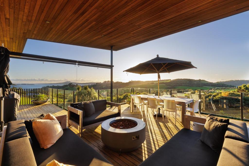 a patio with a table and chairs on a deck at Cable Bay Views in Oneroa