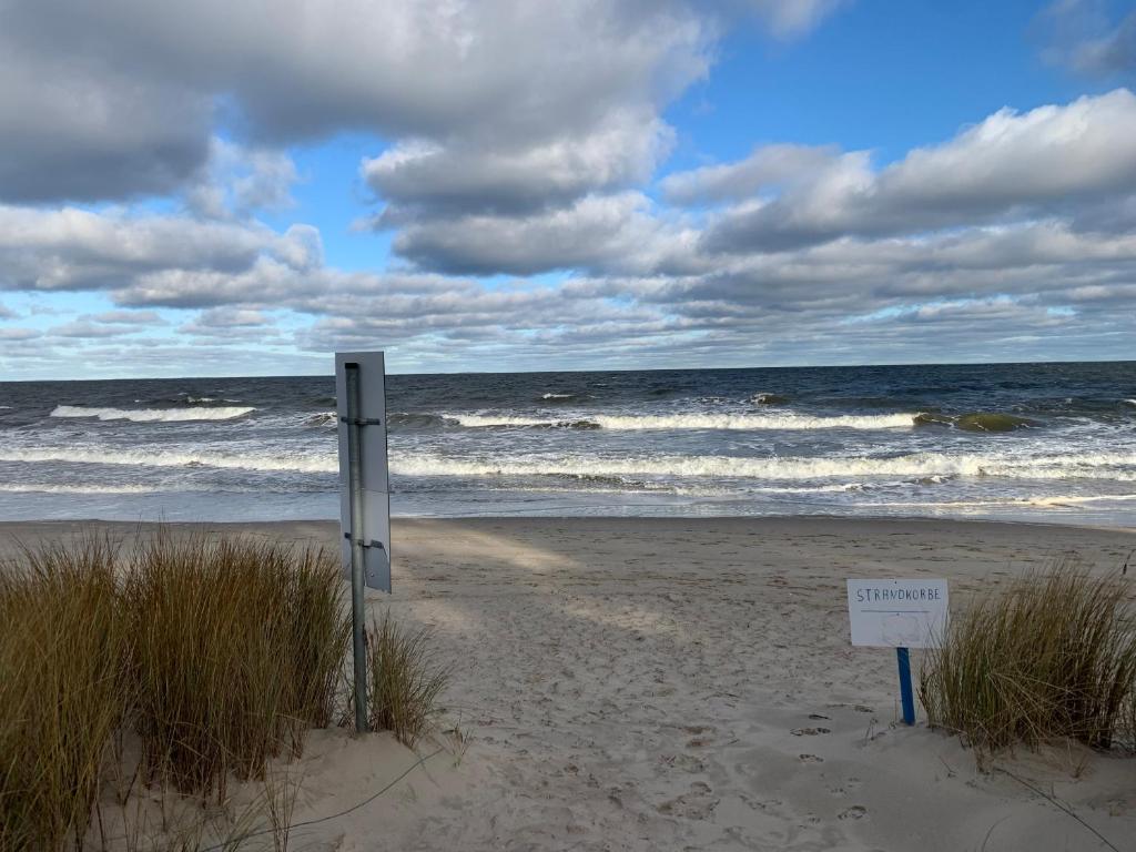 a sign in the sand on a beach with the ocean at Ferienhaus Waldidyll in Zempin