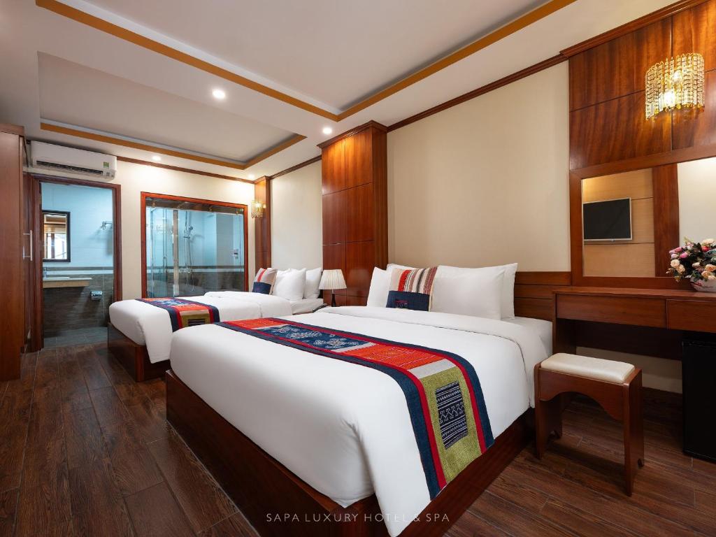a hotel room with two beds and a desk at Sapa Luxury hotel & Spa in Sa Pa