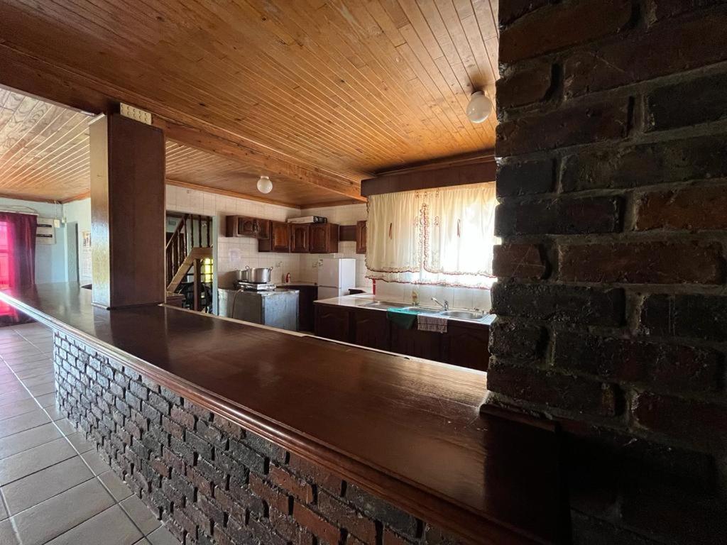 une cuisine avec un comptoir et un mur en briques dans l'établissement Kharimbi Campsite House, à Brakpan
