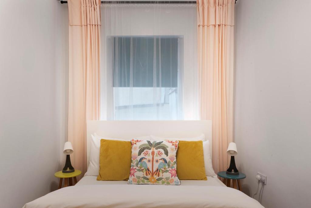 a bedroom with a bed with yellow pillows and a window at Old Street Apartments By Morethanstays in London