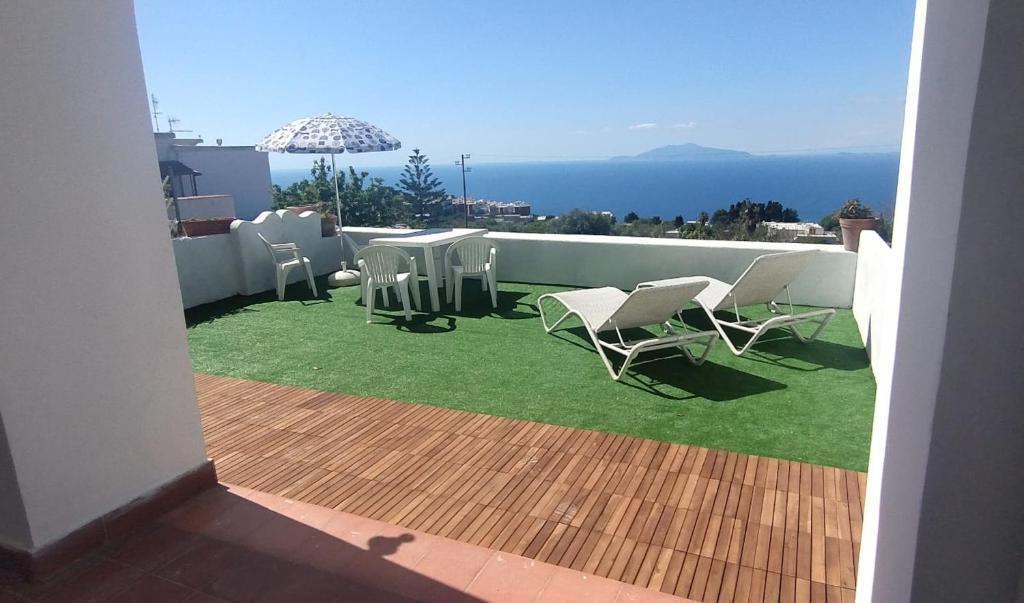 a balcony with chairs and an umbrella on the grass at About Capri in Anacapri