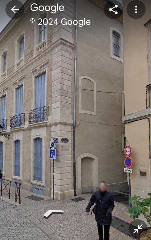 un homme marchant dans une rue devant un bâtiment dans l'établissement Les halles de Béziers, à Béziers