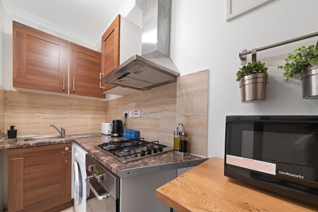 a kitchen with a stove and a microwave at Old Street Apartments By Morethanstays in London