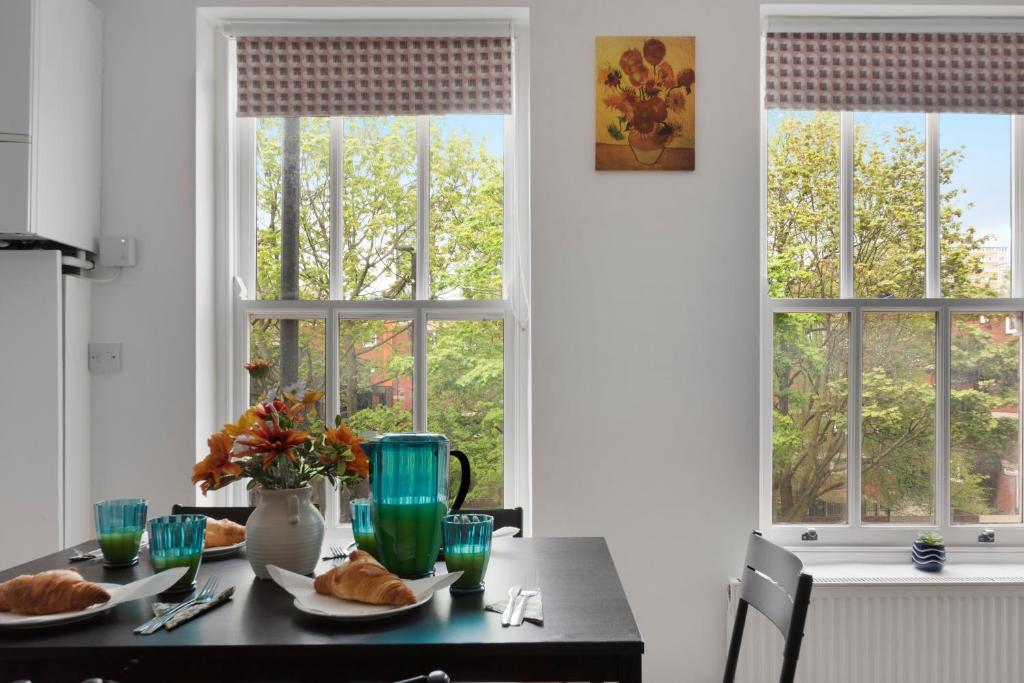 a table with plates of food and two windows at Old Street Apartments By Morethanstays in London