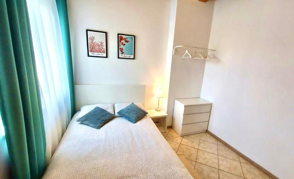een kleine slaapkamer met een bed met twee blauwe kussens bij Fregata in Łeba