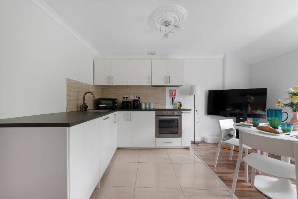 a kitchen with white cabinets and a dining room at Old Street Apartments By Morethanstays in London
