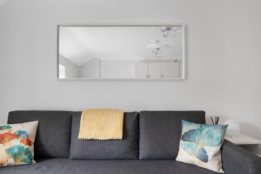 a gray couch with pillows in a living room at Old Street Apartments By Morethanstays in London