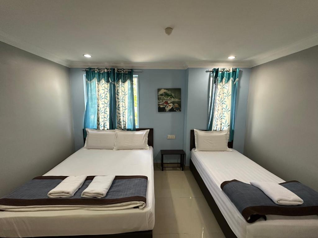 2 camas en una habitación con paredes y ventanas azules en Maha Hotel en Puchong