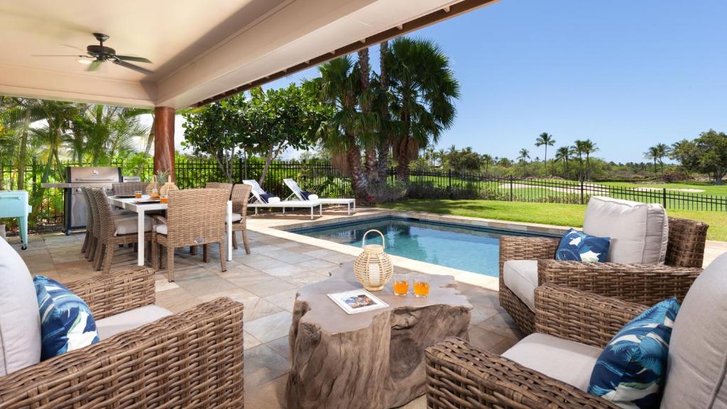 a patio with a table and chairs and a pool at PARADISE AWAITS Idyllic 4BR Single-Level KaMilo Home with Private Pool in Waikoloa