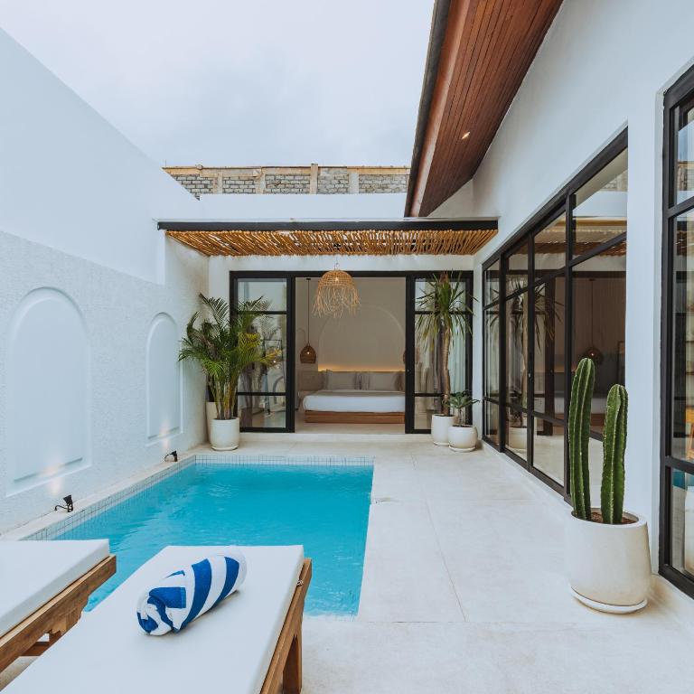 ein Schwimmbad in der Mitte eines Hauses in der Unterkunft The Serendipity Palms Villa by Hombali in Canggu