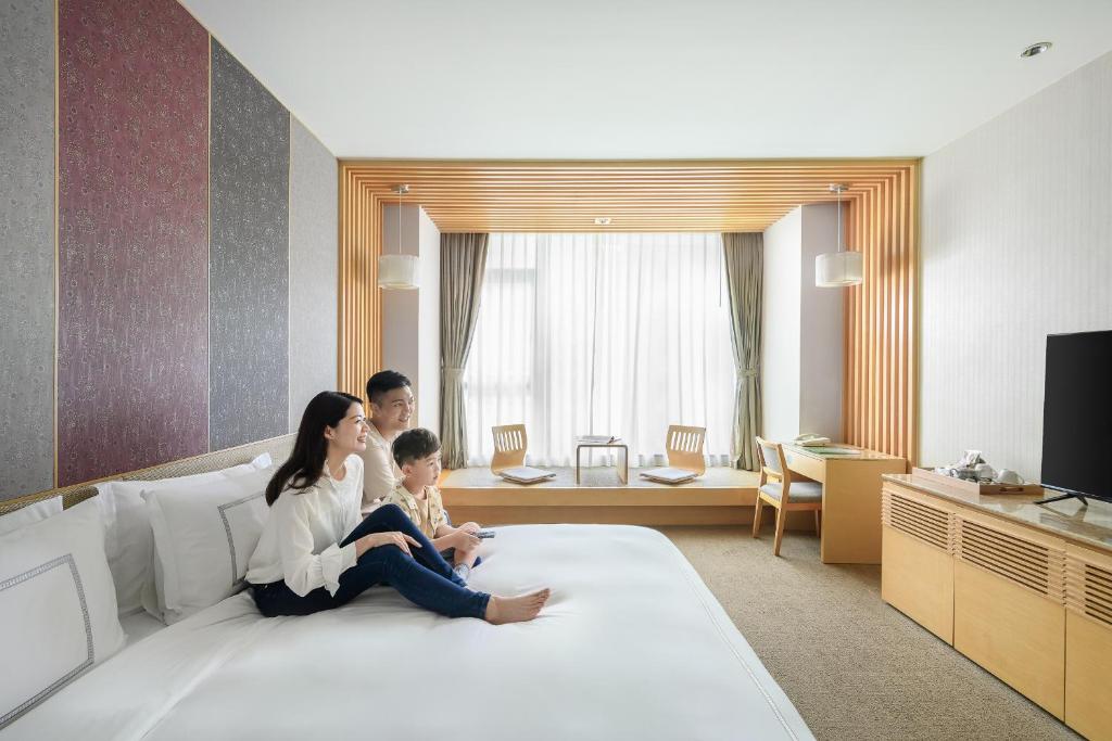 una mujer y un niño sentados en una cama en Evergreen Resort Hotel - Jiaosi, en Jiaoxi