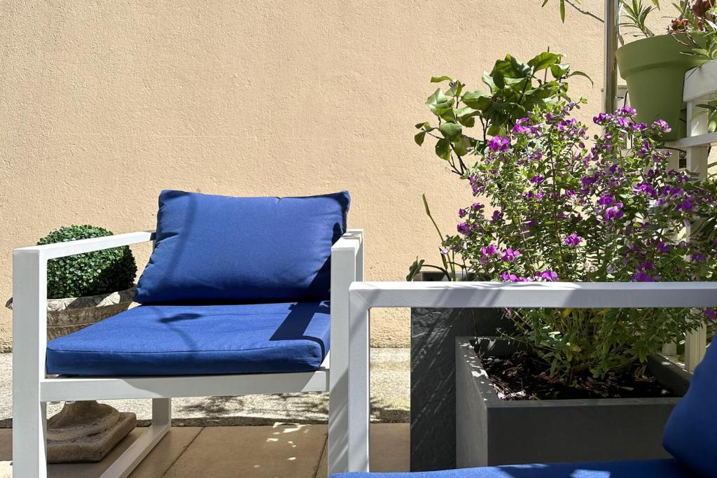 a blue pillow on a chair next to some flowers at Cannes NG - Appartement à 10 mn du Palais des Festivals in Cannes