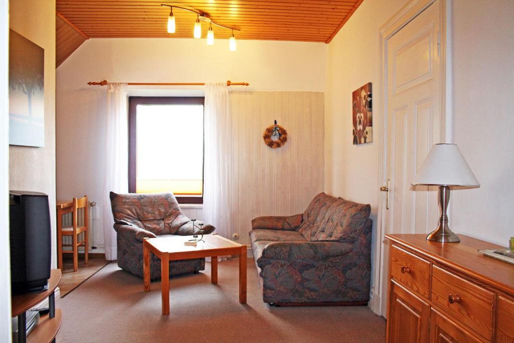 ein Wohnzimmer mit zwei Stühlen und einem Fernseher in der Unterkunft Ferienhof Serck - Kleine Wohnung in Fehmarn