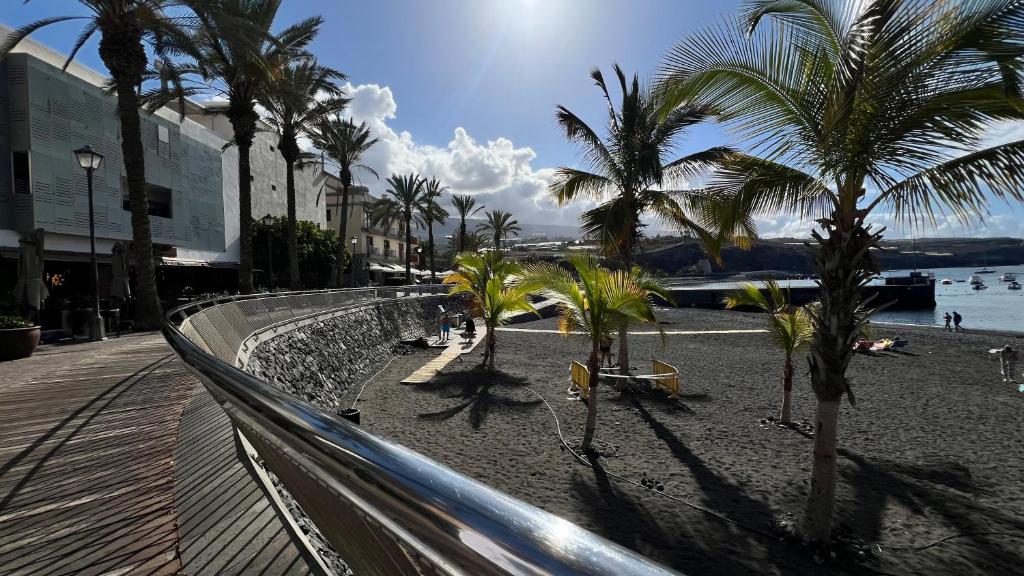 a sandy beach with palm trees and the ocean at ALCAMAR, Penthouse for rent with beautiful views in Playa de San Juan! in Guía de Isora