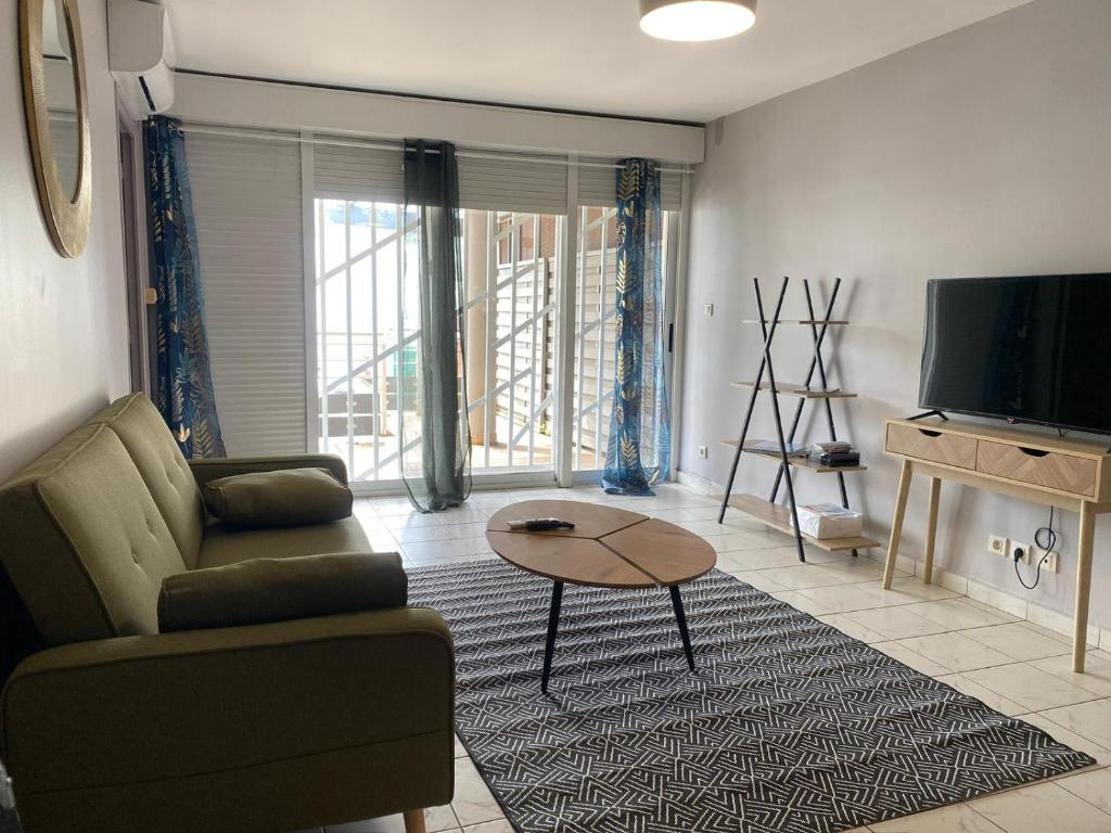 een woonkamer met een bank, een tafel en een tv bij Appartement T2 Kaweni in Mamoudzou