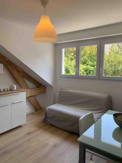 Cette chambre comprend un lit, une table et deux fenêtres. dans l'établissement Joli studio au calme en bord de mer #pornichouette, à Pornichet