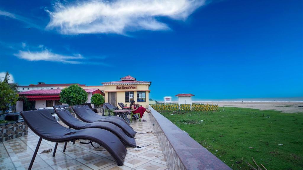 a group of benches in front of a building next to the beach at Sher Bengal Beach Resort in Mandarmoni