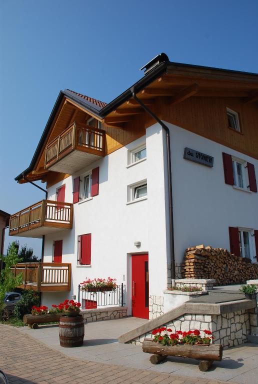 a white building with a red door and red windows at Affittacamere Dai Stoneri in Cavareno