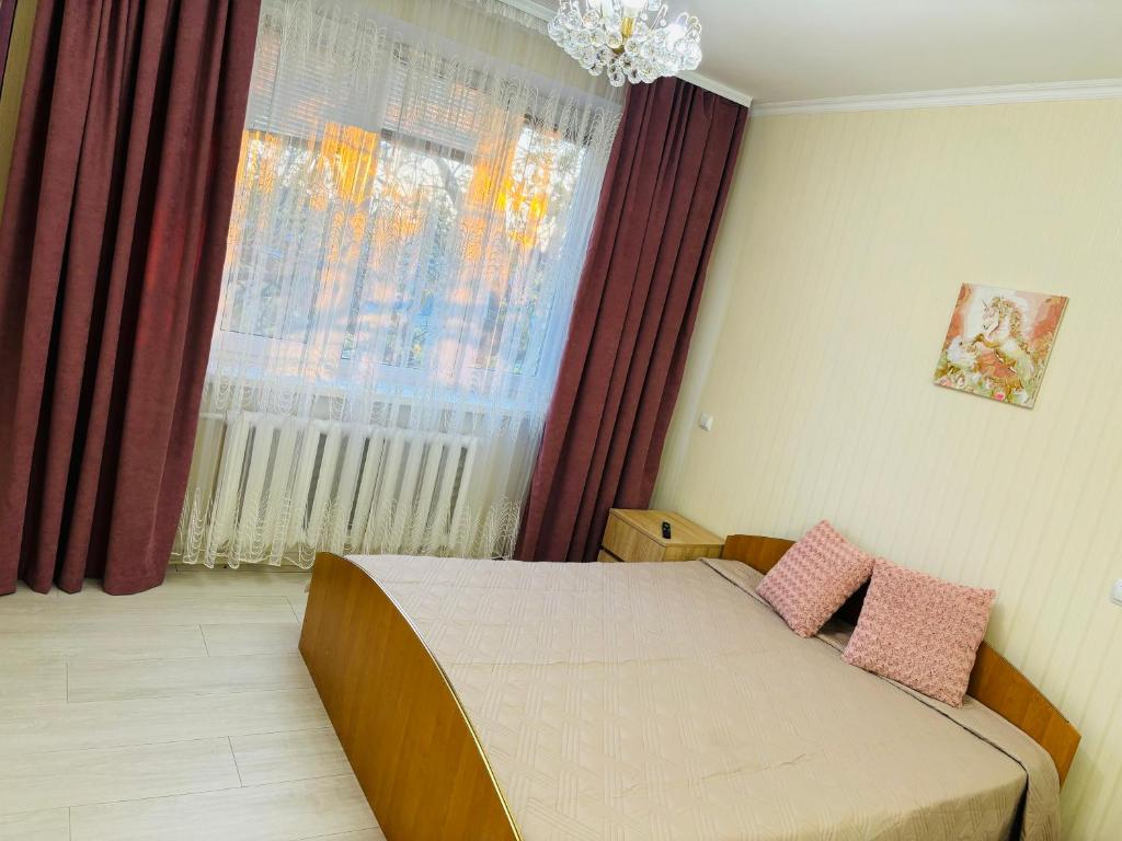 a bedroom with a bed with two pink pillows on it at Paola Apartment in Chişinău