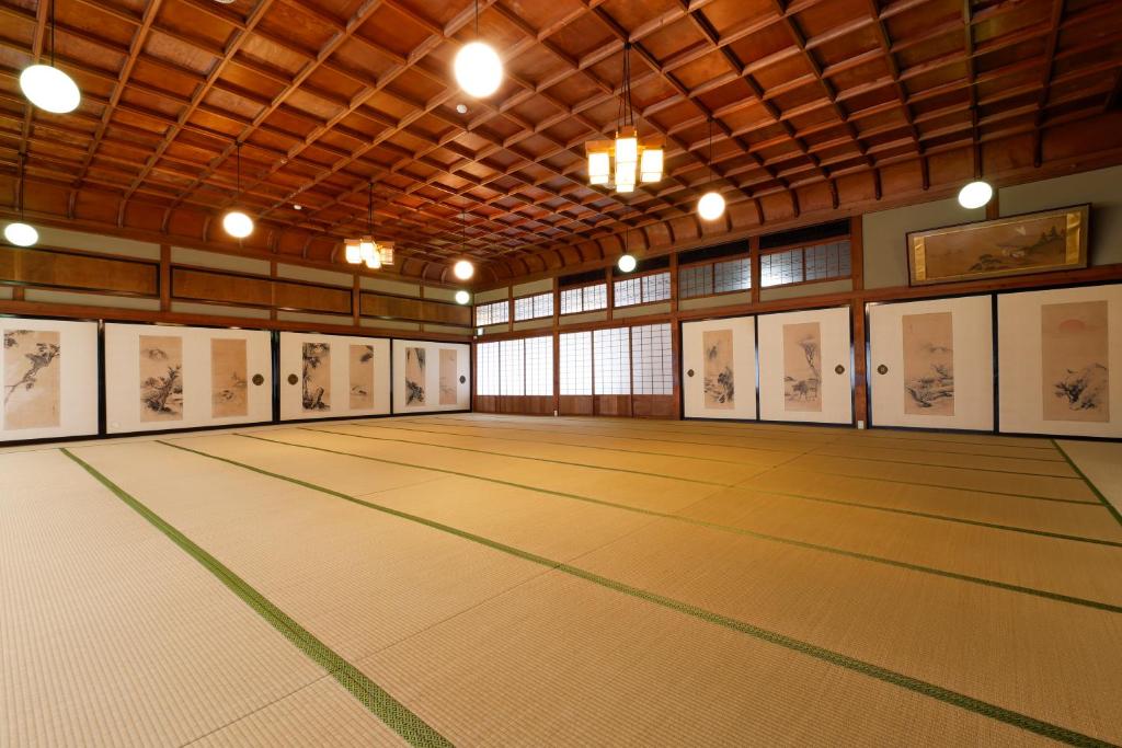 um quarto amplo com piso em madeira e pinturas nas paredes em Seikiro Ryokan Historical Museum Hotel em Miyazu