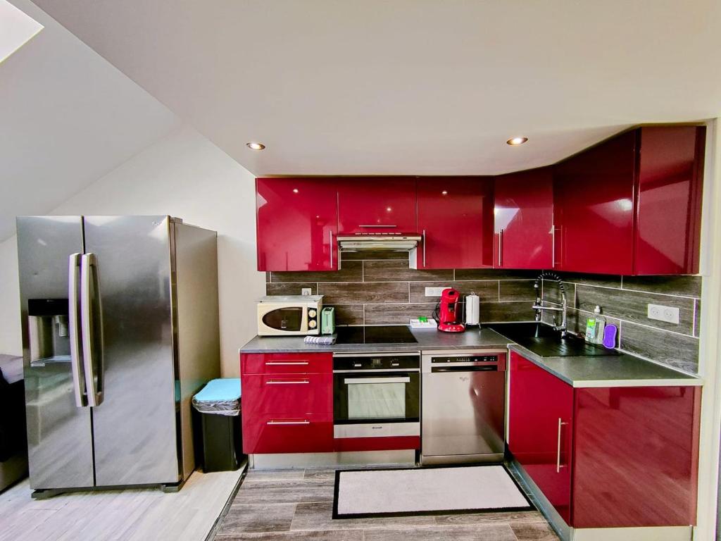 een keuken met rode kasten en een roestvrijstalen koelkast bij Home - Sous les toits de Paris - Séjour à Auxerre in Auxerre