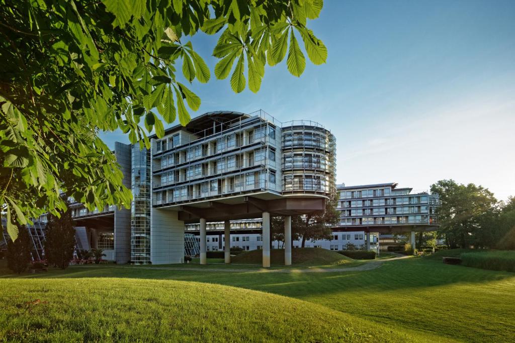 ein Gebäude in einem Park mit einem grünen Feld in der Unterkunft Kongresshotel Potsdam am Templiner See in Potsdam