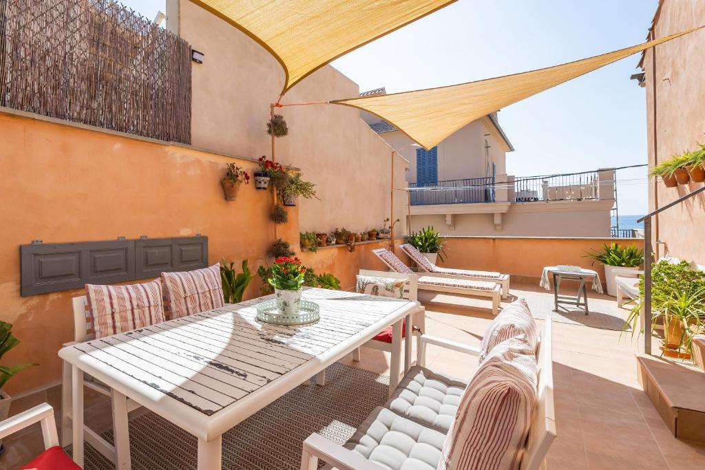 a patio with a table and chairs and an umbrella at Poppy's Beach House in Colònia De Sant Jordi