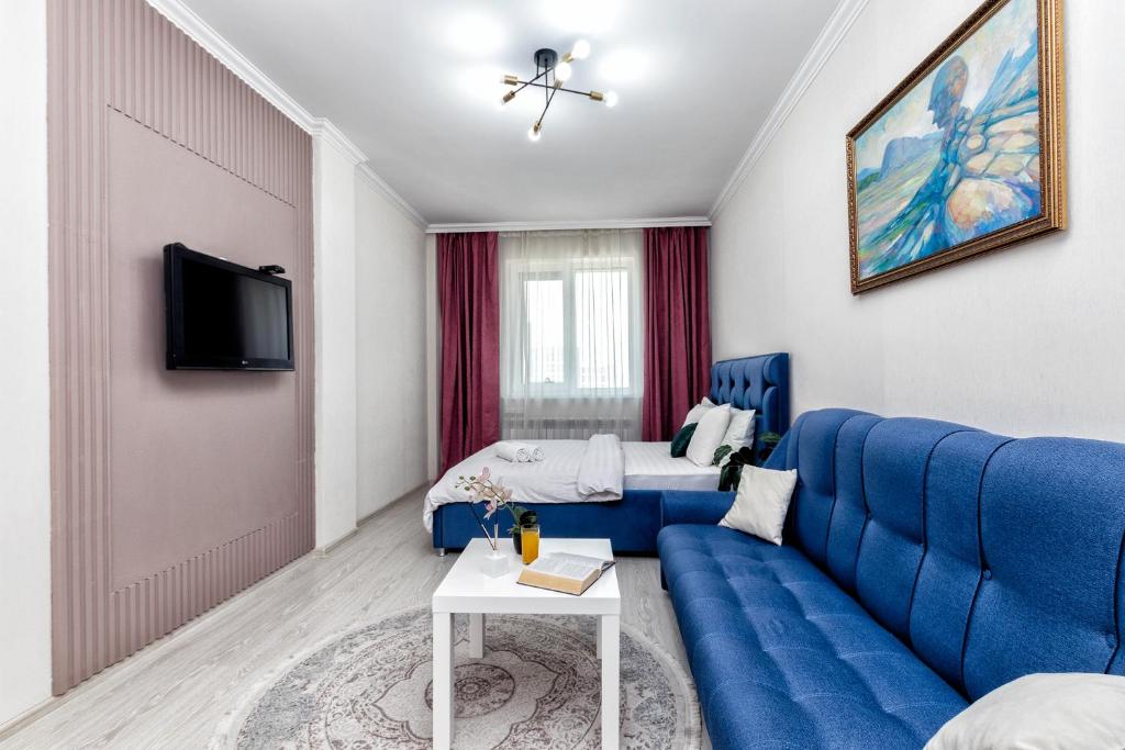 uma sala de estar com um sofá azul e uma cama em Luxurious apartment in the heart of Astana em Astana