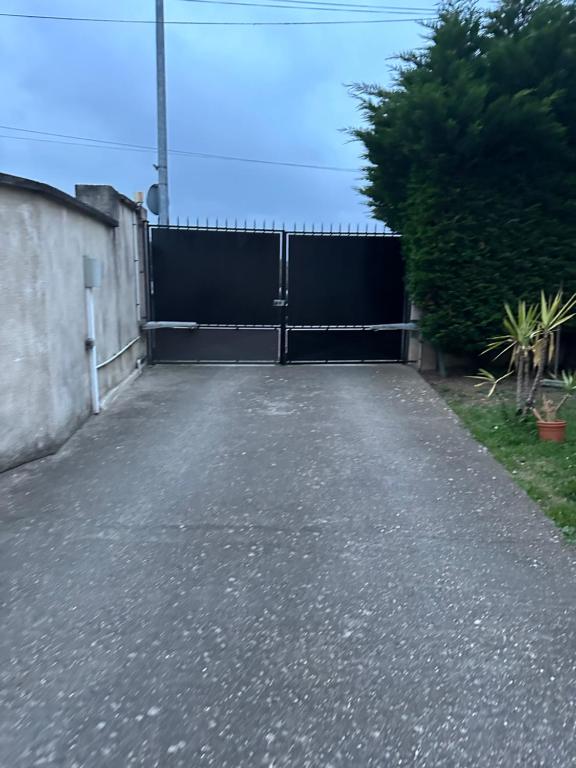 a driveway with a black gate and a fence at Logement entier limay in Limay