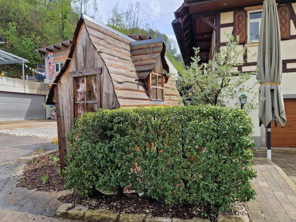 a small wooden house sitting next to a hedge at Schwarzwaldtraum pur! Zauberhaft übernachten in Ottenhöfen