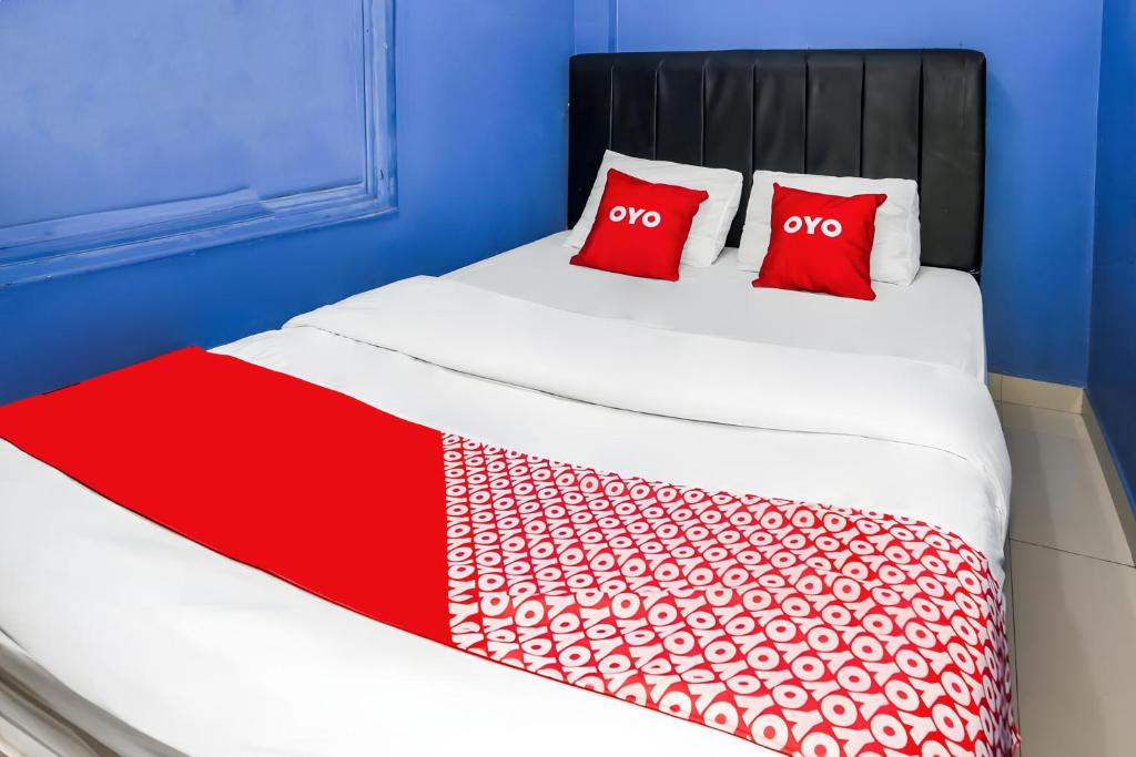 a white bed with two red pillows on it at OYO 93772 Iconiq Rooms in Bekasi