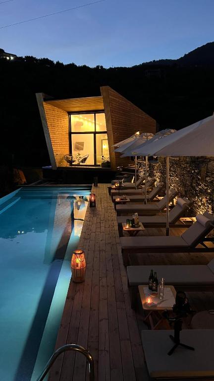 a swimming pool with lounge chairs and umbrellas at night at Five Olive Dream Trip - Luxury Suites with Sea View in Plomari