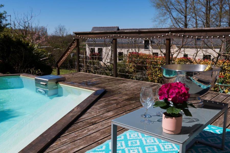 een tafel met wijnglazen en bloemen naast een zwembad bij Les Logis d Ussé in Rigny-Ussé