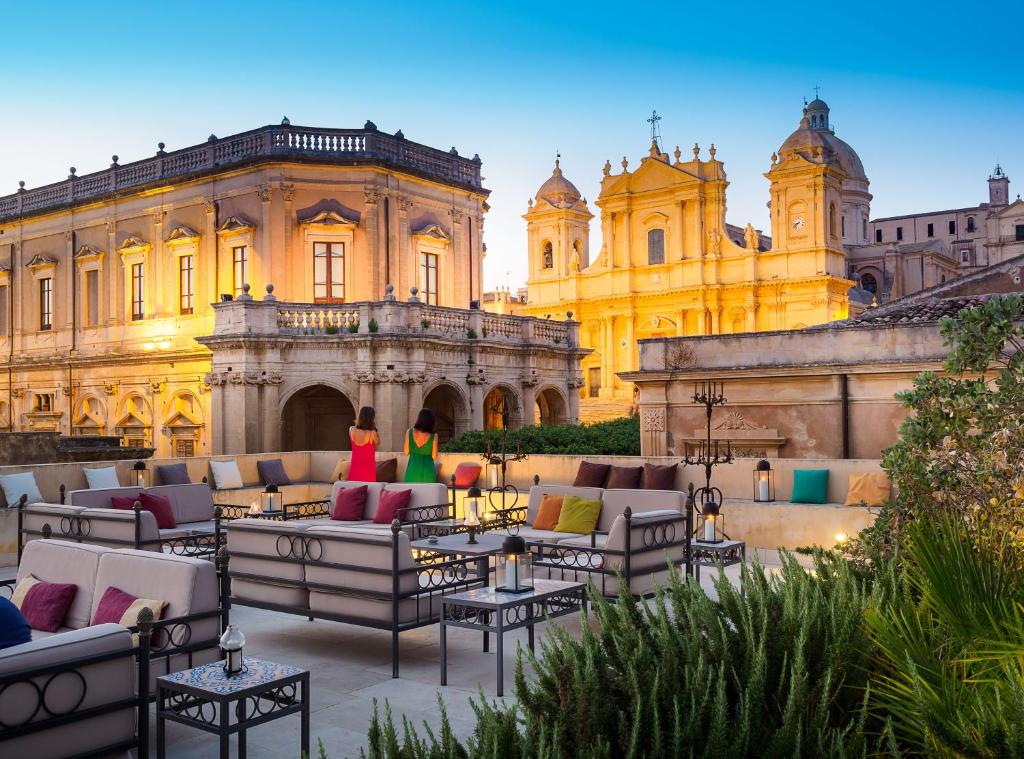 een binnenplaats met banken en tafels voor een gebouw bij Gagliardi Boutique Hotel in Noto