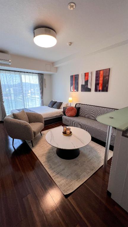 a living room with a couch and a bed at OUCHI HOTEL Hatchobori in Hiroshima