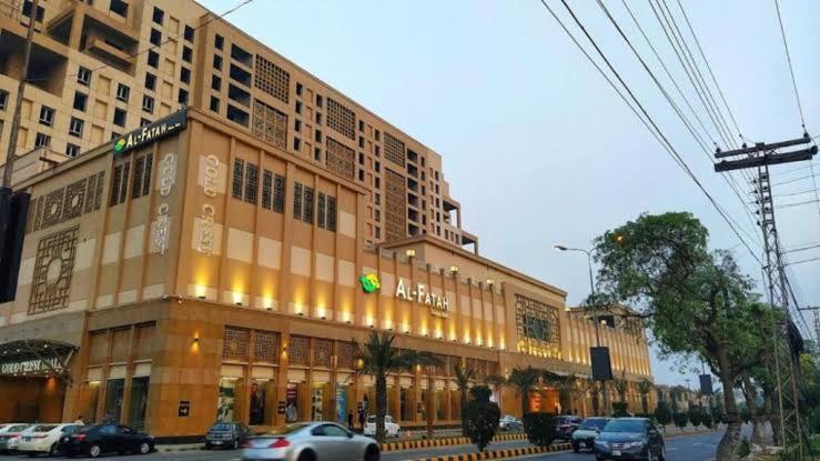 un grand bâtiment avec des voitures garées devant lui dans l'établissement GOLD crest sunset luxury apartment, à Lahore