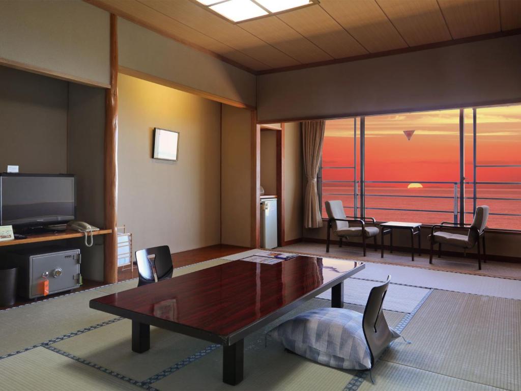 a living room with a table and a dining room at Unohama Onsen Royal Hotel Kobayashi in Joetsu