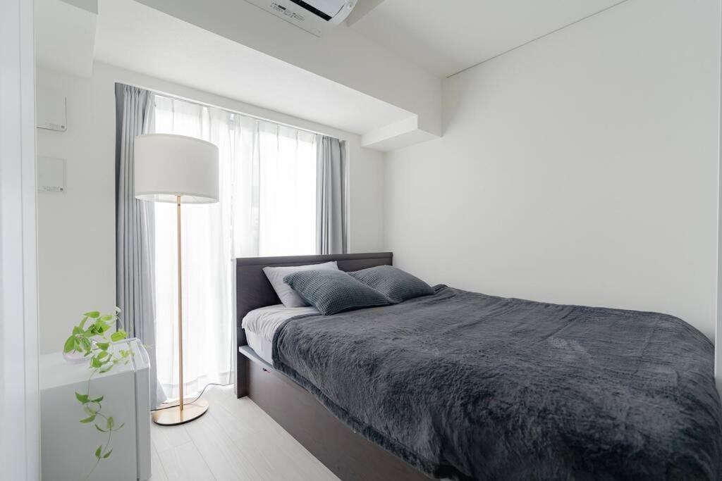 een witte slaapkamer met een bed en een raam bij unito residence HIGASHISHINJUKU in Tokyo