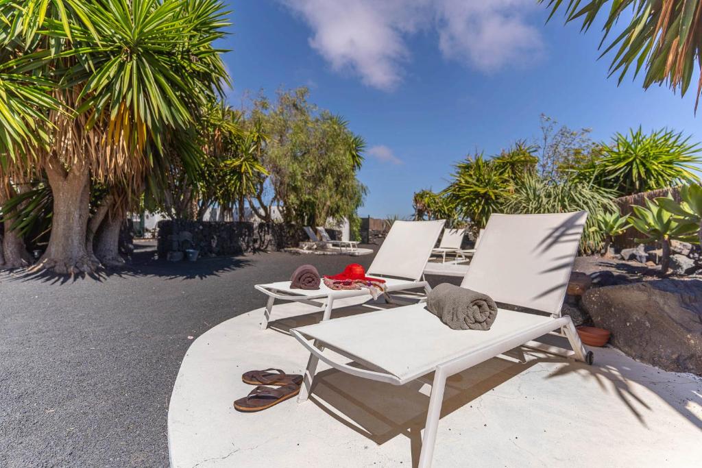 twee witte stoelen op een patio met palmbomen bij Caserio de Mozaga in San Bartolomé