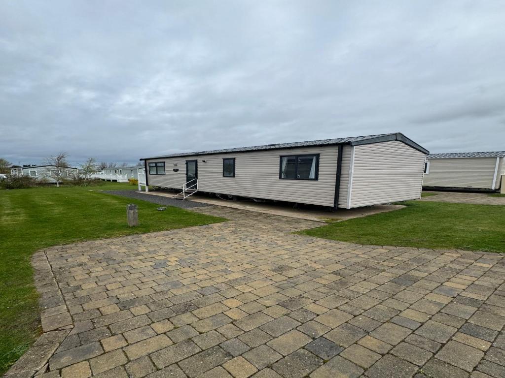 ein weißes Gebäude mit einem großen Hof mit einem Haus in der Unterkunft Lovely 2-Bed Caravan in Prestonpans in Longniddry