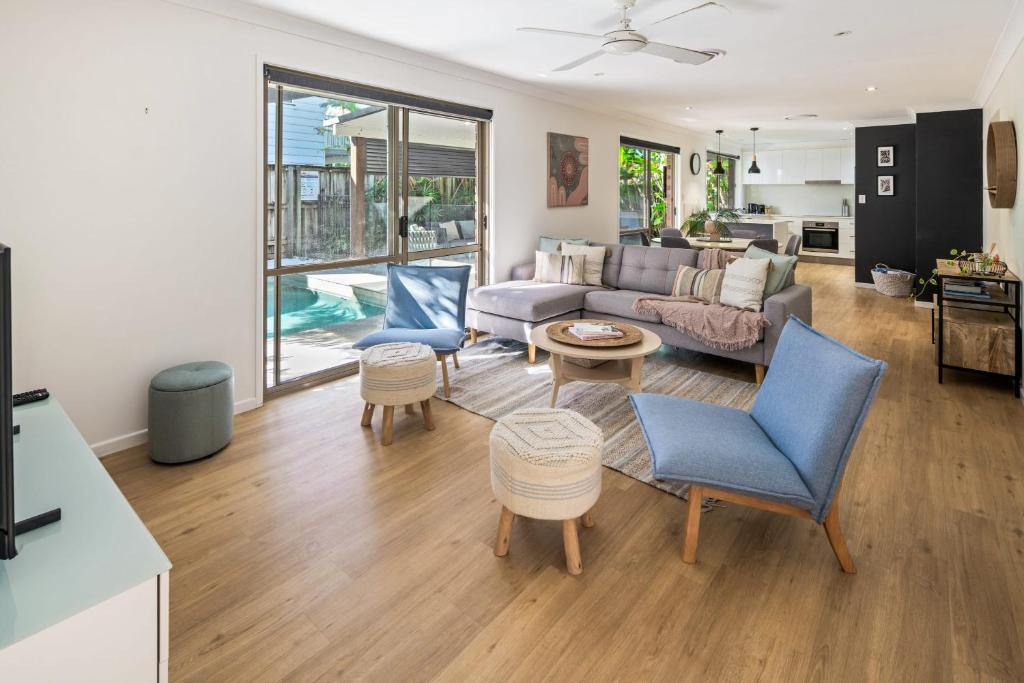 een woonkamer met een bank, stoelen en een tafel bij Sandy Dunes Retreat Walk to Wurtulla Beach in Kawana Waters