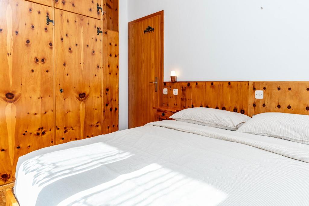 een slaapkamer met een wit bed en houten wanden bij Trilo Luce della Paganella in Andalo