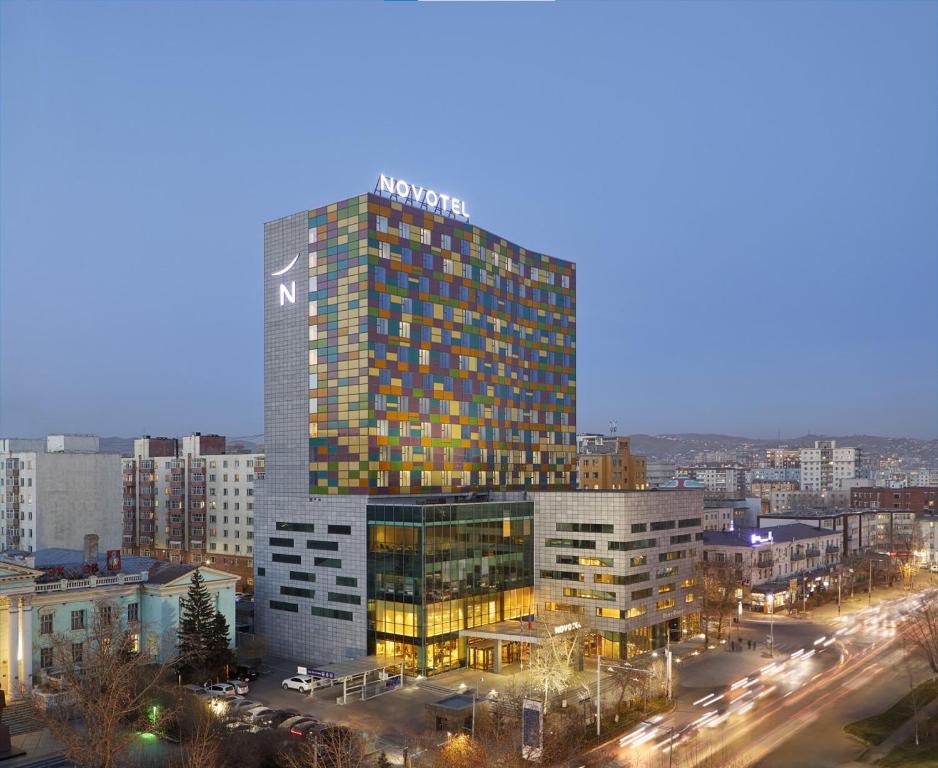 Un grand bâtiment avec un panneau en haut dans l'établissement Novotel Ulaanbaatar, à Oulan-Bator