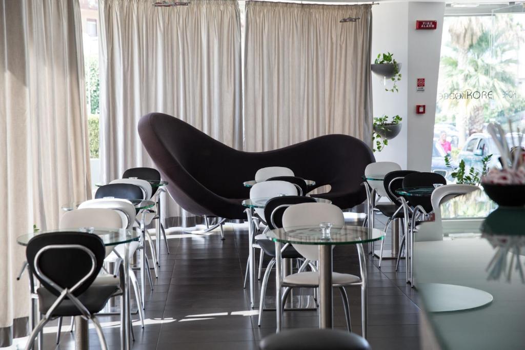 un gruppo di tavoli e sedie in una stanza con pianoforte di Hotel Kore a Villaggio Mosè